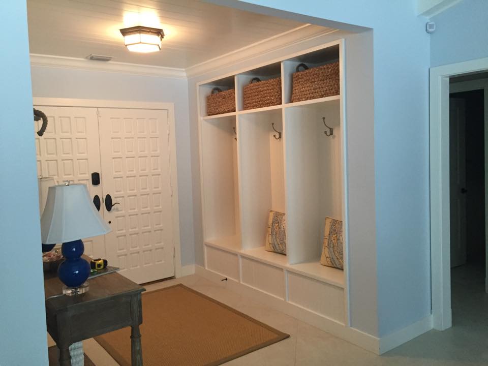 Three-bay mudroom built-in with coat hooks, upper basket storage and a bench with drawers, set into an entry wall.